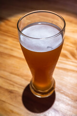 A glass of beer close-up high angle view on a wooden table in a bar - 619738464