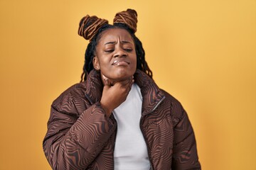 African woman with braided hair standing over yellow background touching painful neck, sore throat for flu, clod and infection