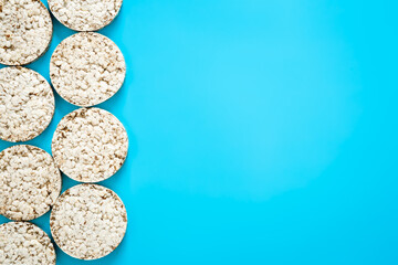Puffed rice cakes on blue background, flat lay, copy space.