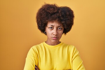 Fototapeta na wymiar Young african american woman standing over yellow background skeptic and nervous, disapproving expression on face with crossed arms. negative person.