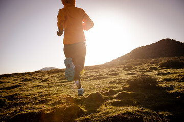 Woman trail runner cross country running at high altitude mountain peak