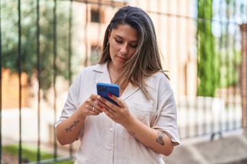 Young hispanic woman using smartphone at street