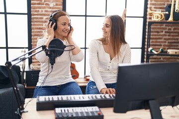 Two women musicians singing song playing piano at music studio