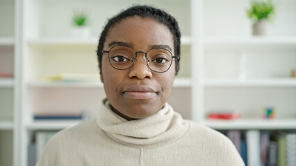 African american woman student standing with serious expression at library university