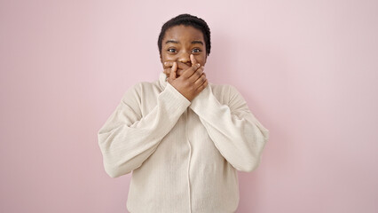 Obraz premium African american woman standing with surprise expression covering mouth with hands over isolated pink background