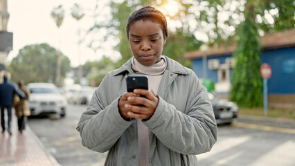 African american woman using smartphone with serious expression at street