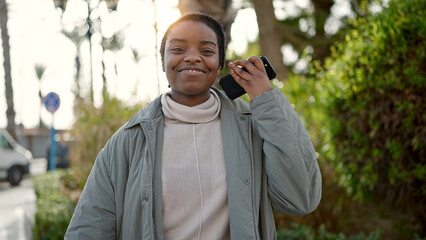 African american woman smiling confident listening to voice message at park