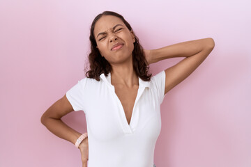 Young hispanic woman wearing casual white t shirt suffering of neck ache injury, touching neck with hand, muscular pain