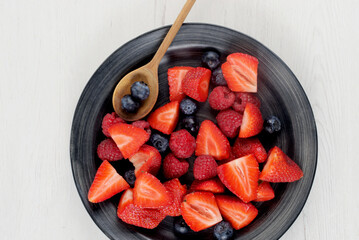 Dish with red fruit on white background