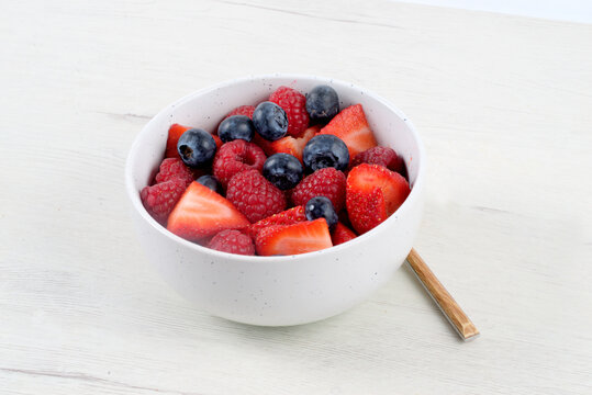 White bowl with red fruits on white background
