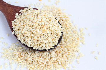 White sesame in a spoon on a white background