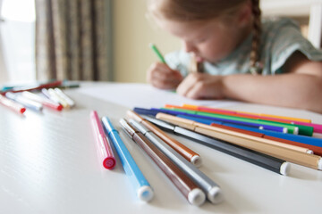 Cute child drawing a picture with colored felt-tip pens. Concept of education