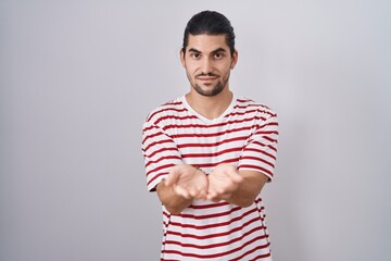 Hispanic man with long hair standing over isolated background smiling with hands palms together receiving or giving gesture. hold and protection