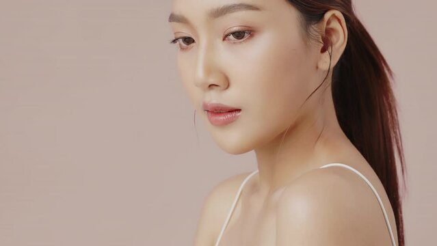Young beautiful Asian woman with natural make up and perfect face looking at camera, Slow motion shot.