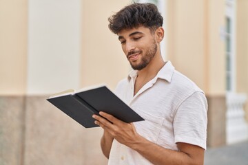 Young arab man smiling confident reading book at street