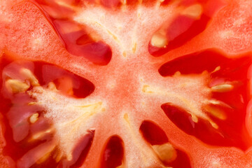 Tomato slice macro, natural background. Juicy red tomato slice closeup with flesh seeds and...