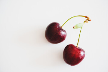 Close-up fresh red cherry of heart shape on white table. Top view