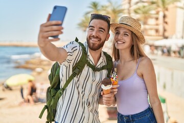 Man and woman tourist couple make selfie by smartphone eating ice cream at seaside