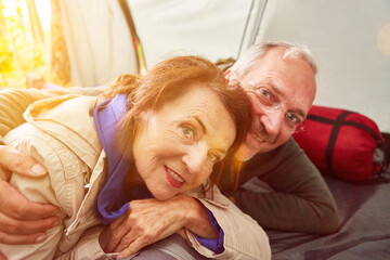 Happy senior couple in love in tent on camping site in summer