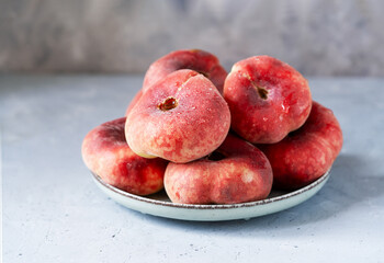 Flat or donut peaches with drops of water in green grey plate on grey concrete background, place for text