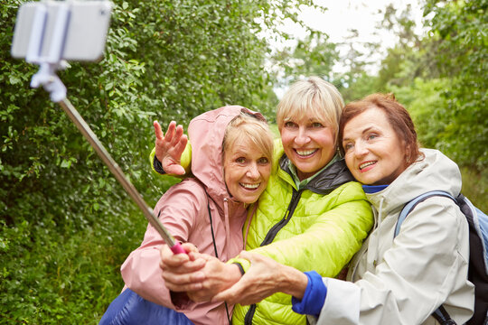 Happy senior woman taking selfie with smartphone on hike