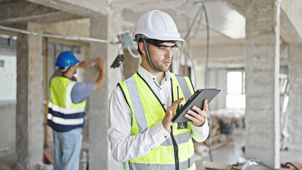 Two men builders using touchpad at construction site