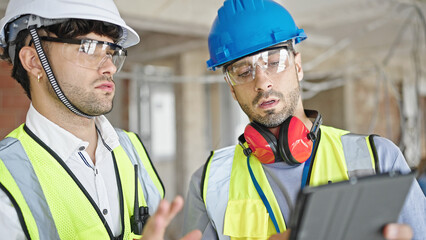 Two men builders using touchpad at construction site