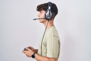 Hispanic teenager playing video game holding controller looking to side, relax profile pose with natural face and confident smile. © Krakenimages.com