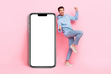 Full length photo of young guy excited winner bet online smartphone screen new parimatch gambling promo isolated on pastel pink color background