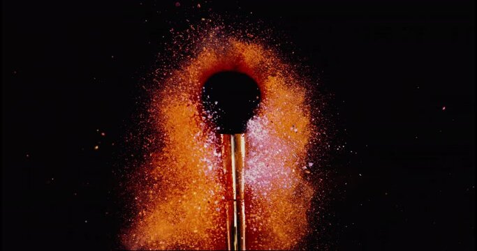 Make up brush and colored powder, particles exploding. Shot with high speed camera. Slow Motion.