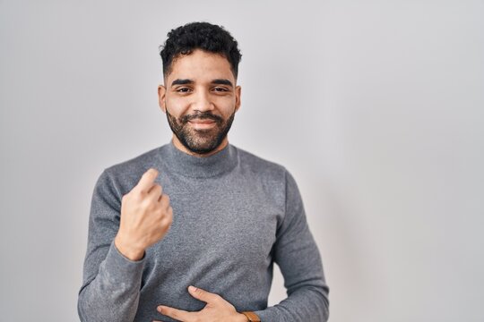 Hispanic man with beard standing over white background beckoning come here gesture with hand inviting welcoming happy and smiling