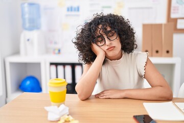 Young middle eastern woman business worker tired sitting on tabl at office