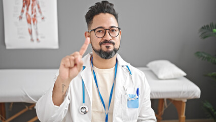 Young latin man doctor saying no with finger at clinic
