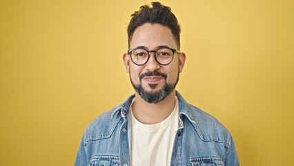 Young latin man smiling confident standing over isolated yellow background