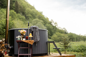Wood-fired hot tub ready for SPA procedures on outdoor terrace in the mountains. Recreation in...