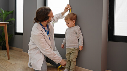 Father and son doctor measuring kid at clinic