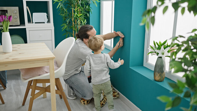 Father and son measuring child on wall at dinning room