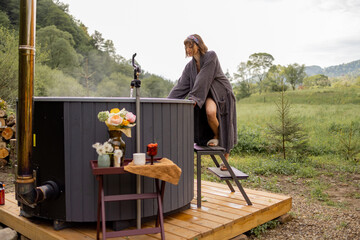 Woman going to bath in hot tub, checking water temperature while resting on nature. Concept of...