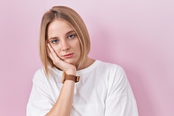 Young caucasian woman standing over pink background thinking looking tired and bored with depression problems with crossed arms.