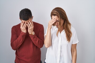 Mother and son standing together over isolated background with sad expression covering face with hands while crying. depression concept.