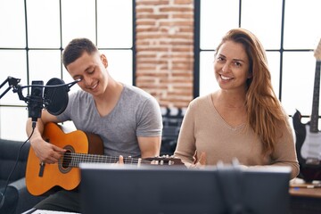 Man and woman musicians playing classical guitar at music studio