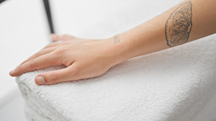 Young beautiful hispanic woman touching folded towels at laundry room