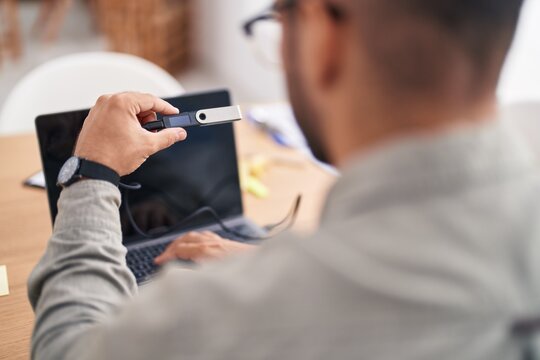 Young hispanic man using crypto cold wallet at office