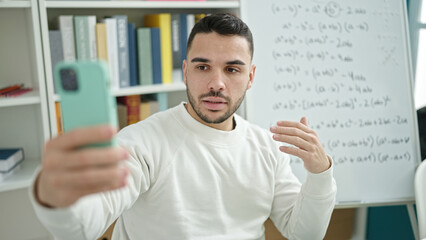 Young hispanic man teacher teaching maths having online lesson at library university