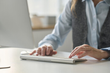 Close-up of busnesswoman typing on keyboard while working on computer at her workplace