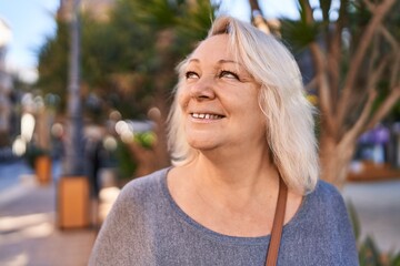 Middle age blonde woman smiling confident standing at park