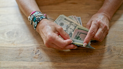 Middle age hispanic woman counting dollars at home