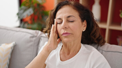 Fototapeta na wymiar Middle age hispanic woman suffering for headache sitting on sofa at home