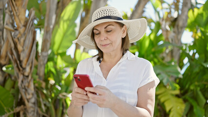 Middle age hispanic woman using smartphone at park
