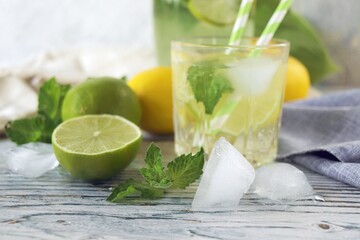 Fresh mojito drink made of lemon, lime, ice and mint leaves, mojito ingredients on a light background, cold seasonal drinks